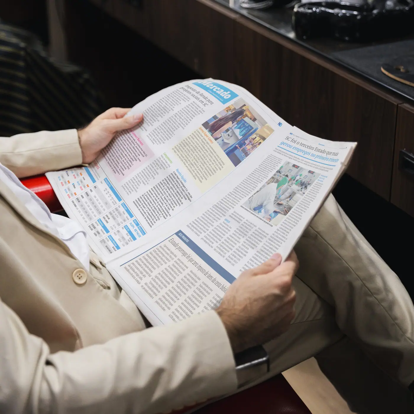 Leitor com terno bege folheando o Jornal ND em uma barbearia